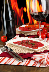 Tasty salami on plates on wooden table on fire background