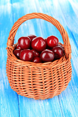Cherry berries in wicker basket on wooden table close-up