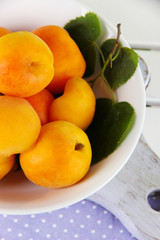 Apricots in plate on board on napkin on wooden table