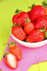 Fresh strawberry in bowl on green wooden background