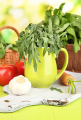 Fresh herb in pitcher on wooden table on natural background