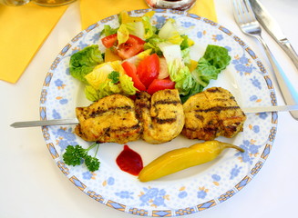 Grilled chicken fillet on metal skewer with salad