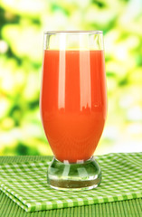 Glass of fresh juice on table on bright background