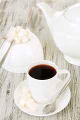 Cup of coffee, teapot and sugar-bowl on color wooden background