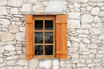 Fototapeta na wymiar Wooden window and shutters in stone wall