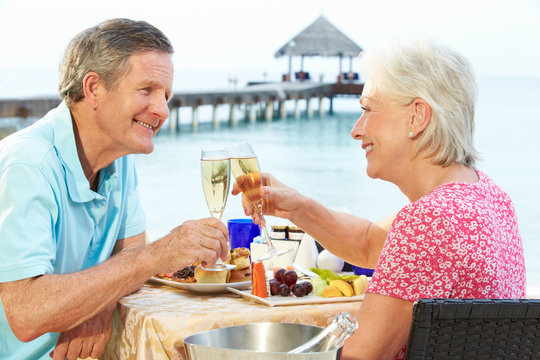 Senior Couple Enjoying Meal In Seafront Restaurant - Powered by Adobe