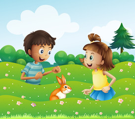 Obraz na płótnie Canvas A girl and a boy with a bunny at the hill