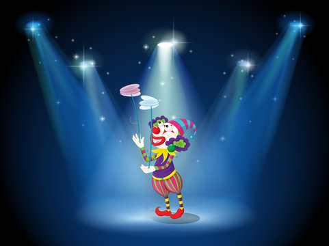 A clown performing on a stage under the spotlights