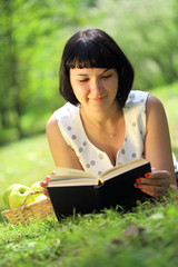 Obraz premium Young woman reading book on grass
