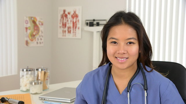 Portrait of female Asian doctor smiling at desk