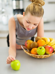 Thoughtful young housewife with plate of fruits