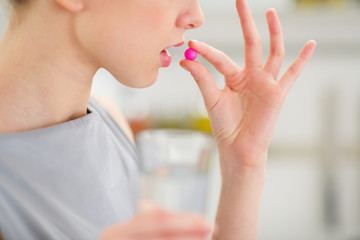 Closeup on young housewife eating pill