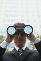 Fototapeta na wymiar Young Businessman Using Binoculars and Looking into the Distance
