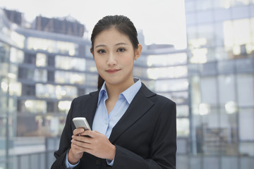 Young businesswoman using her phone, cityscape in background