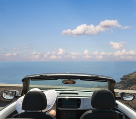 Woman in white hat in an open car