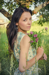 Vintage style photo of a young girl holding clover bouquet