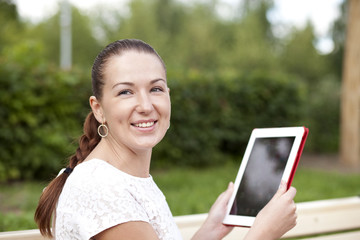 Young woman using a tablet computer on a park