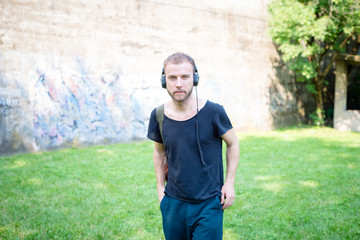 hipster modern stylish blonde man listening music in park