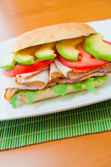 Sandwich with turkey, tomato, avocado and arugula.