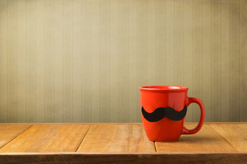 Red cup with paper mustache on wooden table