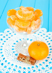 Tasty mandarine's slices in glass bowl on blue background