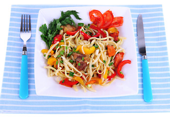 Noodles with vegetables on plate on napkin