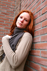 Young woman next to a brick wall