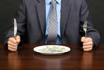 Young businessman having dinner dollars on black background