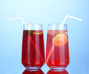 Two cherry cocktails with ice on dark blue background