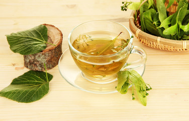 Glass cup of tea with linden on wooden table close-up