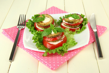 Tasty roasted marrow and tomato slices with salad leaves,