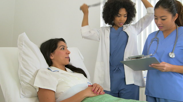 Female multiracial doctor listening to her patient's heartbeat