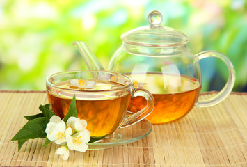 Cup of tea with jasmine, on bamboo mat, on bright background