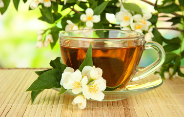 Cup of tea with jasmine, on bamboo mat, on bright background