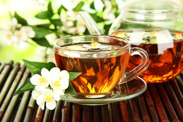 Cup of tea with jasmine, on bamboo mat, close-up