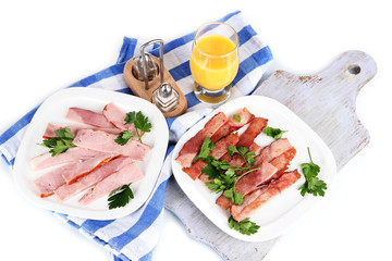 Bacon on plates on napkin on board isolated on white