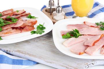 Bacon on plates on napkin on board isolated on white