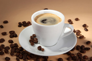Cup of coffee with coffee beans on beige background
