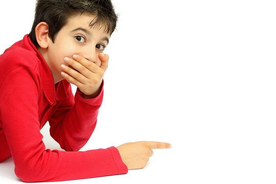 Young boy with hand over his mouth pointing to something