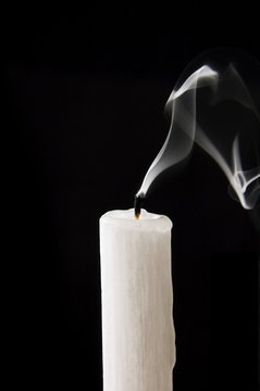 Extinguished candle with smoke over black background