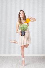 Pretty dancer with a watering can and a plant