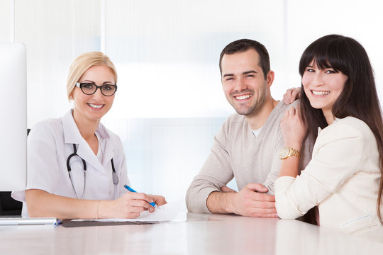 Happy Doctor Discussing With Couple
