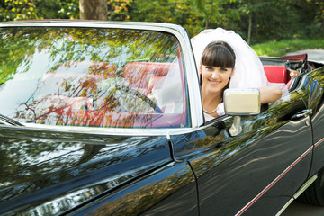 smiling bride driving convertible car outdoors