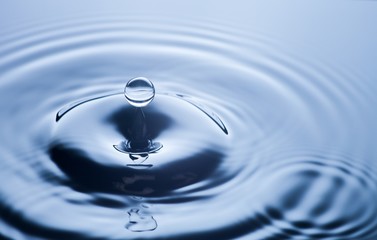 Fototapeta na wymiar Water drop close up, clear blue background