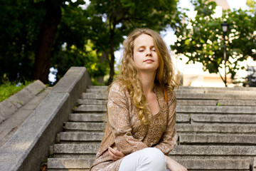 Obraz premium beautiful blonde woman relaxes on the steps in the park