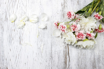 Bouquet of white peonies and pink carnations on wooden back