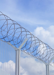 Chain link fence with barbed wire under blue sky