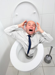 Frightened businessman screaming from toilet bowl.