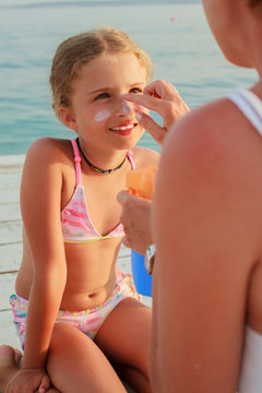 Sun protection - Mother anoints her daughter face sunblocker