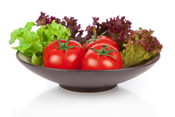 tomatoes and green salad in the bowl, over white background